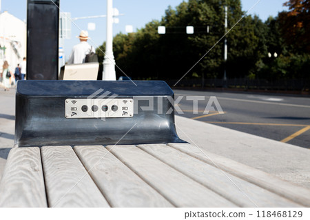 Modern bench with Wi-Fi and USB connectors for charging phone at public transport stop in city, accessible environment in town 118468129