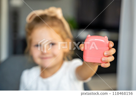 Little girl with a stamp with a name for signing children's things. Identification of personal clothing. Focus on stamp Little girl with a stamp with a name for signing children's things. Identification of personal clothing. Focus on stamp 118468156