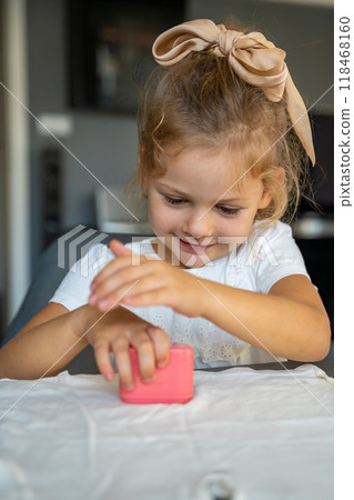 Little girl with a stamp with a name for signing children's things. Identification of personal clothing.  118468160