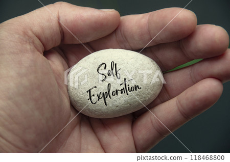 Hand holding Zen stone with Self Exploration text engraved on the stone Hand holding Zen stone with Self Exploration text engraved on the stone 118468800