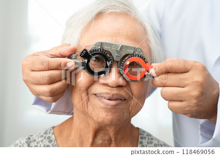 Asian senior woman wearing ophthalmic vision eye test and using optical trial frame. 118469056
