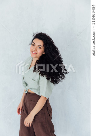 Curly brunette woman in summer clothes smiling Curly brunette woman in summer clothes smiling 118469484