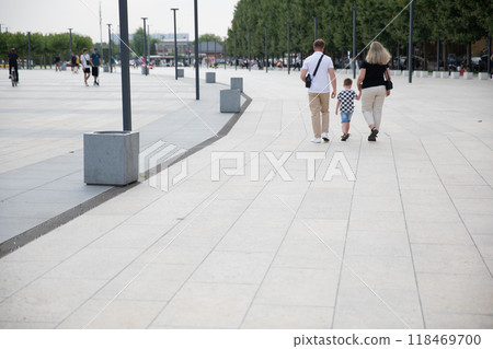Mom and dad holding the child's hands walking outside 118469700