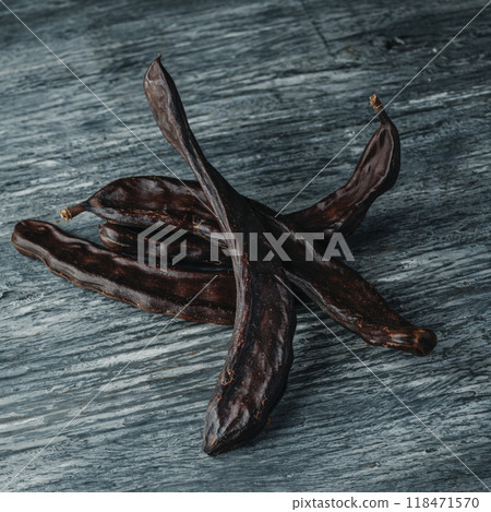 some ripe carob pods on a gray rustic table some ripe carob pods on a gray rustic table 118471570