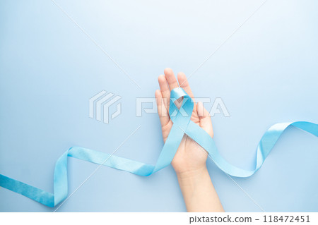 Men's health and Prostate cancer awareness campaign in November. Man hands holding light blue ribbon awareness on sky blue background. Symbol for support men who living with cancer. Copy space. Men's health and Prostate cancer awareness campaign in November. Man hands holding light blue ribbon awareness on sky blue background. Symbol for support men who living with cancer. Copy space. 118472451