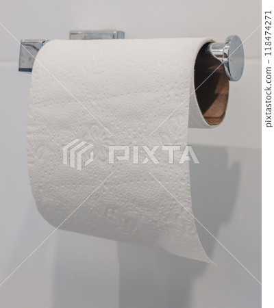 A roll of white toilet paper hanging on a brushed metal holder in a modern bathroom A roll of white toilet paper hanging on a brushed metal holder in a modern bathroom 118474271