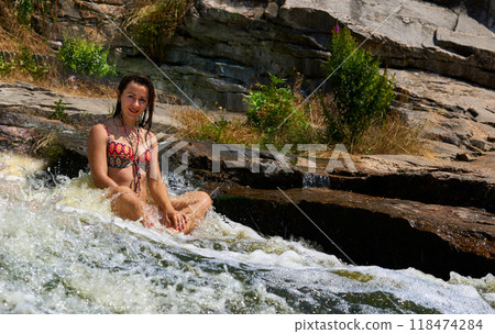 Beautiful girl enjoys swimming in a stream of a rapid mountain river at resort Beautiful girl enjoys swimming in a stream of a rapid mountain river at resort 118474284