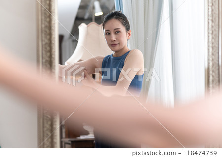 A woman wearing sportswear worries about her upper arms in front of a mirror A woman wearing sportswear worries about her upper arms in front of a mirror 118474739