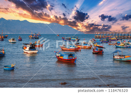 Vietnamese traditional fishing boats at sea in Vietnam against backdrop of mountains at sunset 118476320