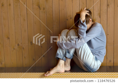 Depressed woman sits shrunken and closes her hands against problems. Closed posture Depressed woman sits shrunken and closes her hands against problems. Closed posture 118476526