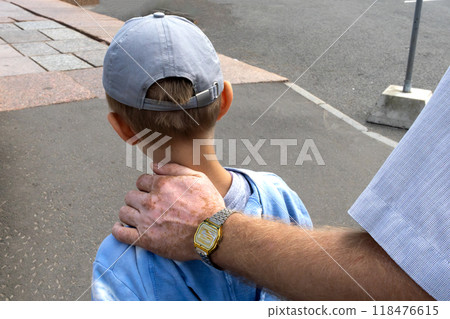 Father's hand on his son's shoulder. Walking and socializing with child. Desire to support, to guide. Child-parent relationship.Life with vitiligo Father's hand on his son's shoulder. Walking and socializing with child. Desire to support, to guide. Child-parent relationship.Life with vitiligo 118476615