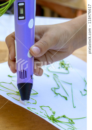 Child's hand creates figures with a 3D pen. Close-up Child's hand creates figures with a 3D pen. Close-up 118476617