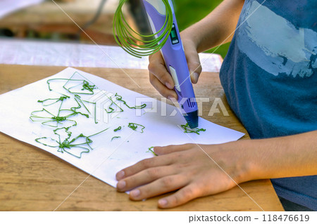 Boy draws figures on paper with 3D pen. Close-up 118476619
