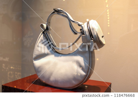 Fashionable beige leather bag in shape of croissant on store window Fashionable beige leather bag in shape of croissant on store window 118476668