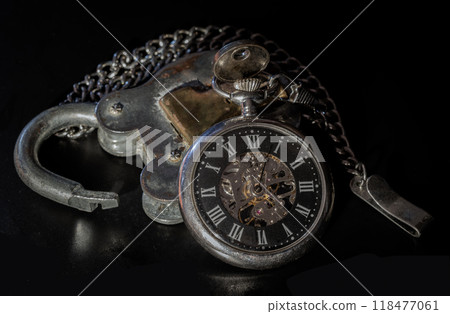 A retro pocket watch on Old vintage iron padlock on dark background. A retro pocket watch on Old vintage iron padlock on dark background. 118477061