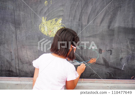 一個三年級小學女生用粉筆在大黑板上畫畫的後視圖 118477649