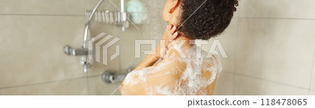A woman bathing with soap on her back, washing her long hair 118478065