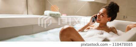 a woman is taking a bath and talking on a cell phone 118478085