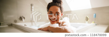 The woman is happily bathing in a jacuzzi tub, smiling with joy 118478099
