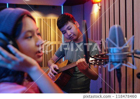 Singing and Playing Guitar in Professional Recording Studio 118478460