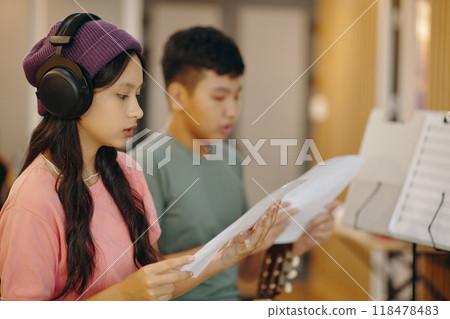 Practicing Singing in Studio with Headphones and Music Sheets Practicing Singing in Studio with Headphones and Music Sheets 118478483