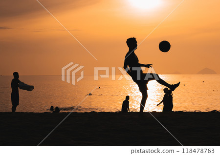 Silhouette of a man kicking a ball playing traditional Asian beach football on beach by the sea at sunset Silhouette of a man kicking a ball playing traditional Asian beach football on beach by the sea at sunset 118478763