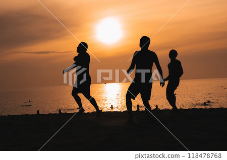 Silhouettes of Asian men playing beach soccer on beach by the sea at sunset Silhouettes of Asian men playing beach soccer on beach by the sea at sunset 118478768