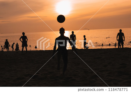 Silhouettes of a group of Asian men playing traditional beach soccer on a beach by sea at sunset 118478771