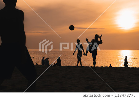 Silhouettes of a group of Asian men playing traditional beach football on beach by the sea at sunset 118478773