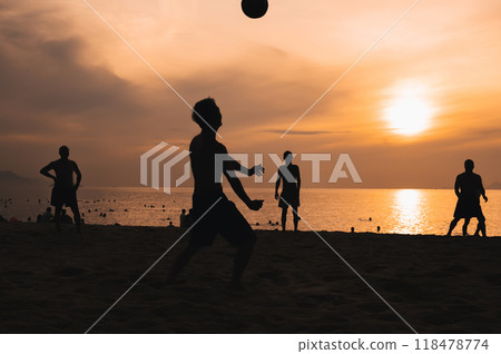 Silhouettes of a group of Asian men playing traditional beach soccer on a beach by sea at sunset 118478774