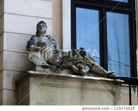 Figure of a girl lying on vacation. Stone statue on the old building. Figure of a girl lying on vacation. Stone statue on the old building. 118478838