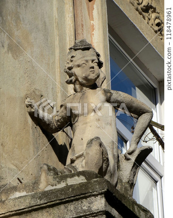 Stone figure statue boy on the balcony by the window of the old building 118478961
