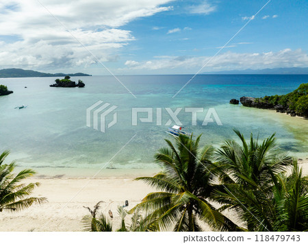 Boat floating over clear sea water in white beach, view from coconut trees in Cobrador Island. Romblon, Philippines. Boat floating over clear sea water in white beach, view from coconut trees in Cobrador Island. Romblon, Philippines. 118479743