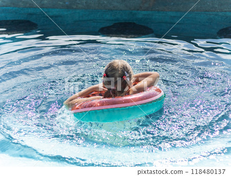 little girl with inflatable ring swims in swimming pool 118480137