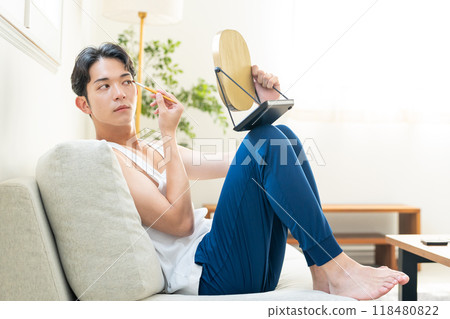 Young man putting on make-up in the living room Young man putting on make-up in the living room 118480822
