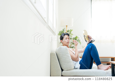 Young man putting on make-up in the living room Young man putting on make-up in the living room 118480825