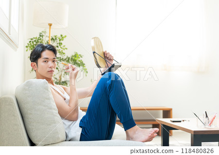 Young man putting on make-up in the living room Young man putting on make-up in the living room 118480826