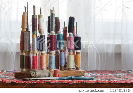 Sewing multicolored threads of soft pastel vintage colors on spools. Sewing tailor related accessories. 118481526