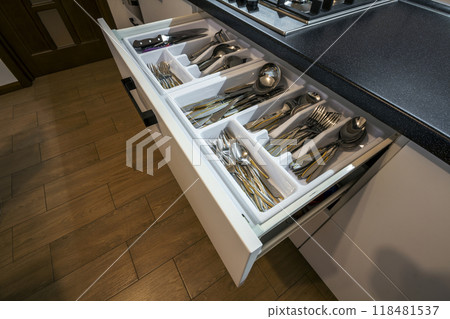 Stainless steel spoons, forks and knifes in cutlery box drawer in white kitchen cupboard Stainless steel spoons, forks and knifes in cutlery box drawer in white kitchen cupboard 118481537