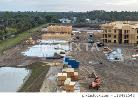 Unfinished frames of apartment condos with wooden roofs under construction. Development of residential housing in US suburbs. Real estate market in the USA Unfinished frames of apartment condos with wooden roofs under construction. Development of residential housing in US suburbs. Real estate market in the USA 118481548