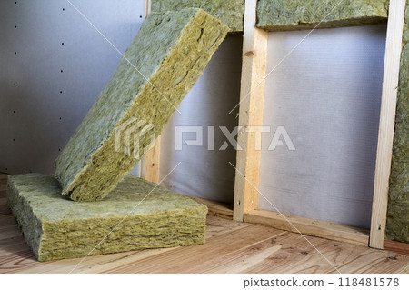 Wooden frame for future walls with drywall plates insulated with rock wool and fiberglass insulation staff for cold barrier. Comfortable warm home, economy, construction and renovation concept. Wooden frame for future walls with drywall plates insulated with rock wool and fiberglass insulation staff for cold barrier. Comfortable warm home, economy, construction and renovation concept. 118481578