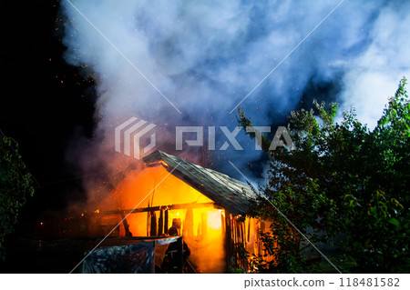 Wooden house or barn burning on fire at night. Wooden house or barn burning on fire at night. 118481582