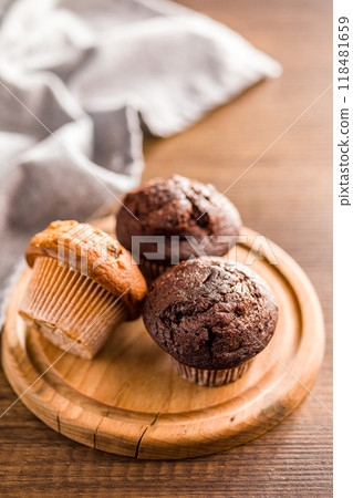 Sweet muffin cakes on cutting board on wooden table. 118481659