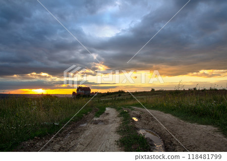Dirt road among dark fields at sunset with dramatic cloudscape. Dirt road among dark fields at sunset with dramatic cloudscape. 118481799