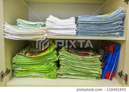 Interior of white plastic cabinet or clothing wardrobe with open doors with stacked pile of clean colorful linen. Household and order, furniture design concept. 118481845