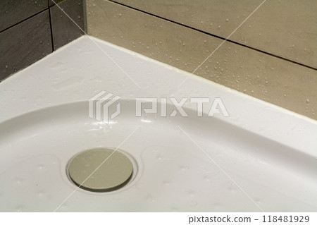 Close-up detail of new modern clean empty white shower cabin with drops of water on nice light beige ceramic tiles on floor and walls. Comfort and hygiene concept. 118481929