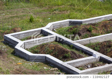 Building site in green field. Close-up detail of trenches dug in ground and filled with cement as foundation for future house. Building, construction, investment and real property concept. Building site in green field. Close-up detail of trenches dug in ground and filled with cement as foundation for future house. Building, construction, investment and real property concept. 118482127