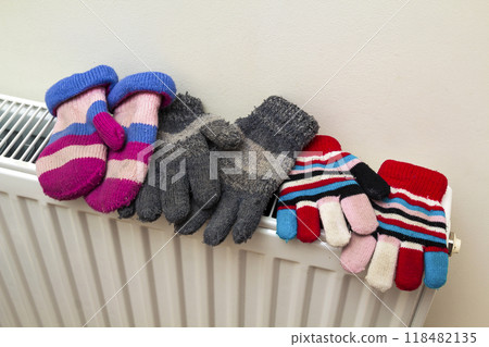 Children's warm hand knitted striped woolen gloves drying on hea Children's warm hand knitted striped woolen gloves drying on hea 118482135