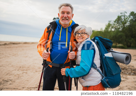 Hiking tourism adventure. Senior couple man woman enjoying outdoor recreation hiking on beach. Happy old people backpackers hikers enjoy walking hike trekking tourism active vacation beauty of nature 118482196