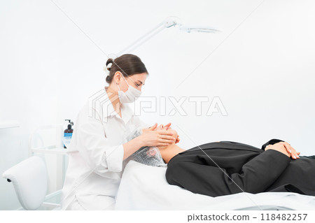 The young female client of cosmetic salon having a cleansing facial mask The young female client of cosmetic salon having a cleansing facial mask 118482257
